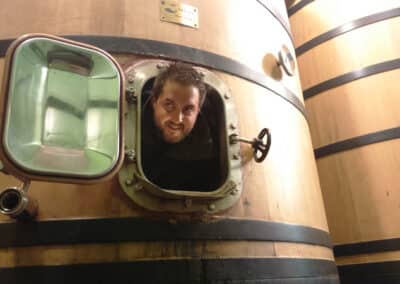 A man poking his head out of a wooden fermentation vat