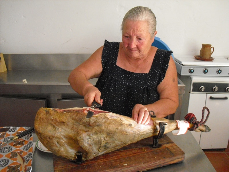 A woman cutting Iberian ham in a kitchen