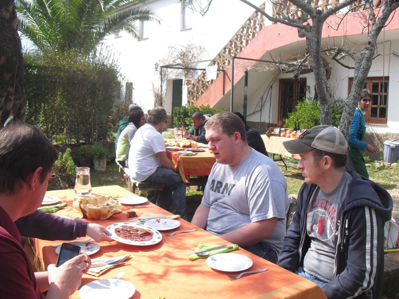 A group of people sitting around tables for lunch in the open air at an Iberian pig farm