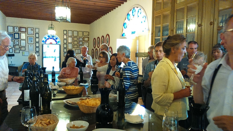 A large group of peoñle standing up in a room tasting sherry